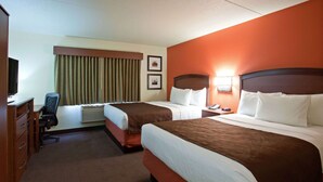 A hotel room with two beds, a desk with a chair, a television, and a window with curtains. - AmericInn by Wyndham Grafton (Grafton)