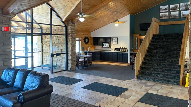 A spacious lobby with a leather couch, a stone fireplace, a kitchen area, and a staircase. - Motel 6 Norway, MI (Norway)