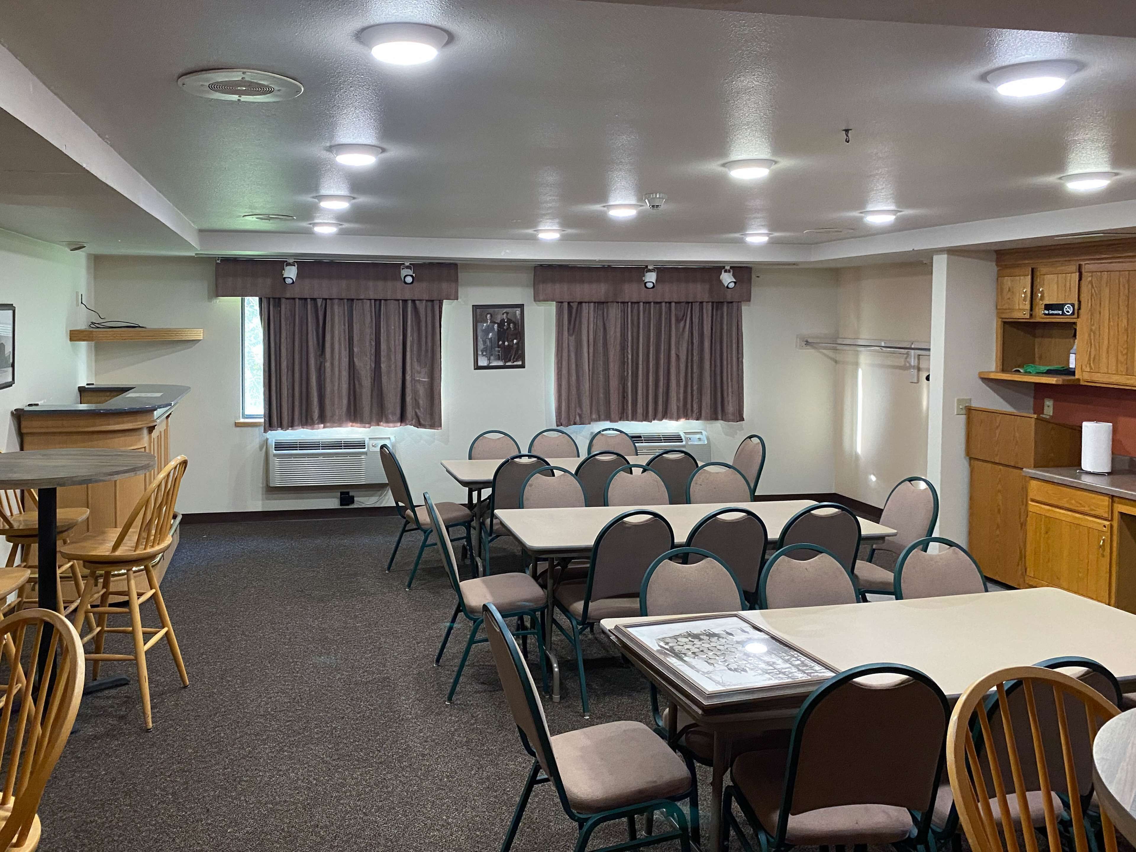 A conference room with a long table, multiple chairs, an air conditioning unit, and a kitchenette area.