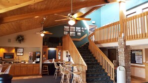 A spacious interior with a wooden staircase, a bar area, and a dining space with wooden chairs and tables. - Motel 6 Norway, MI (Norway)