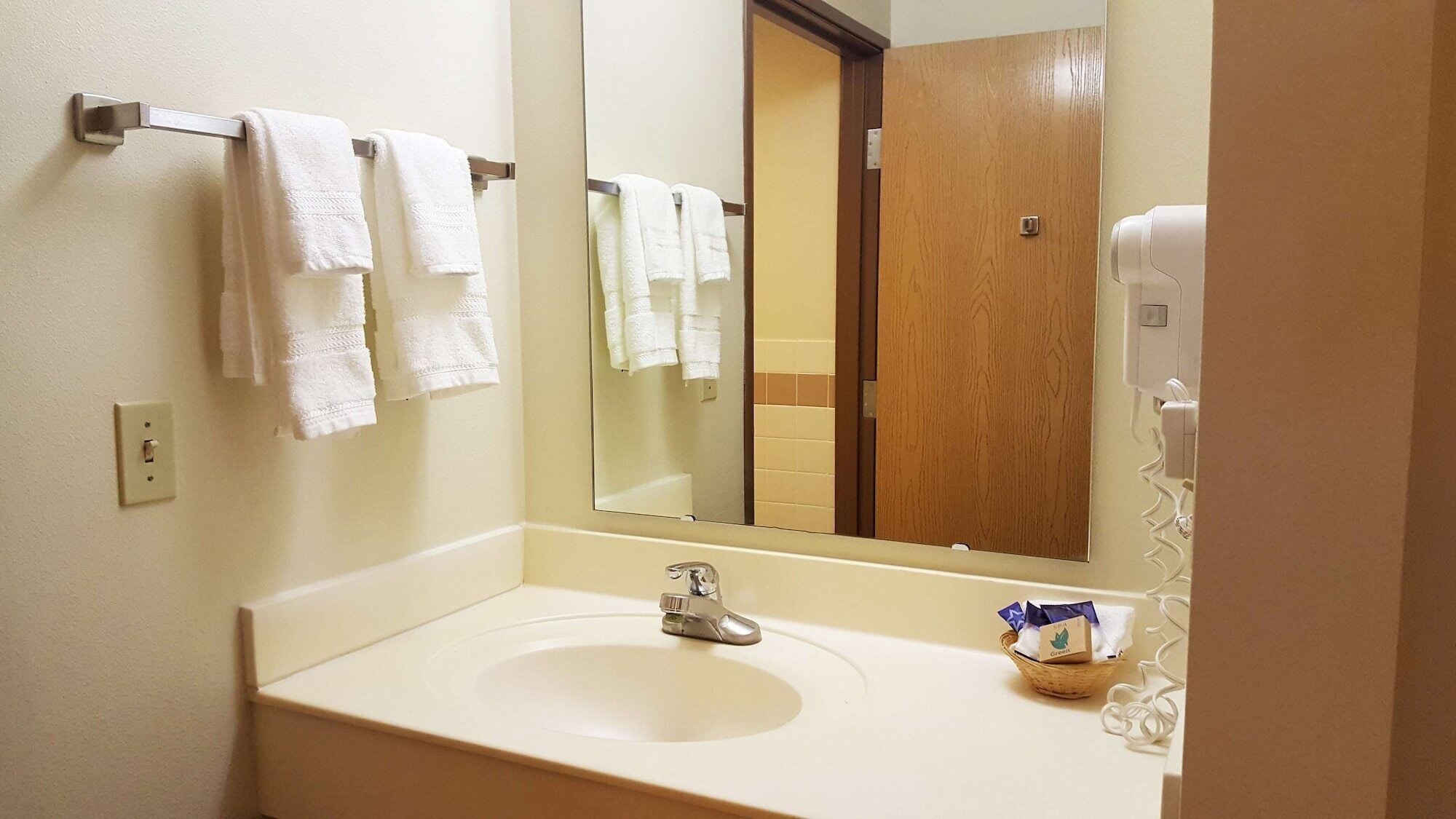 A hotel bathroom with a sink, a mirror, and a towel rack with multiple towels.