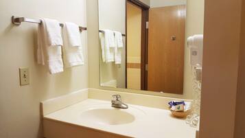 A hotel bathroom with a sink, a mirror, and a towel rack with multiple towels.
