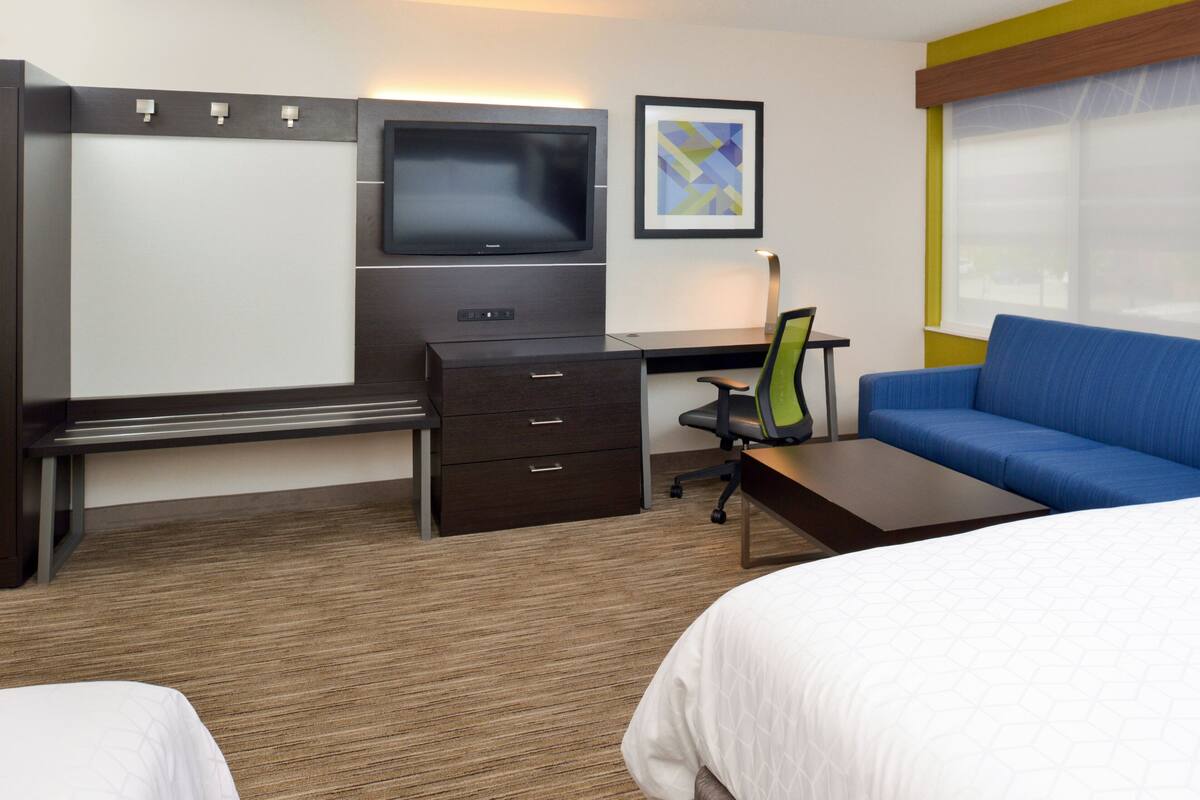 Une chambre d’hôtel comprenant un lit, un bureau avec une chaise, une télévision et un canapé.