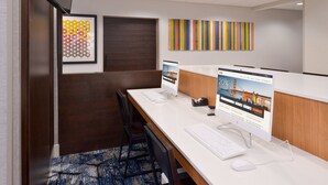 Een vergaderzaal met een lange tafel, stoelen, een whiteboard en een computer waarop een website wordt getoond.