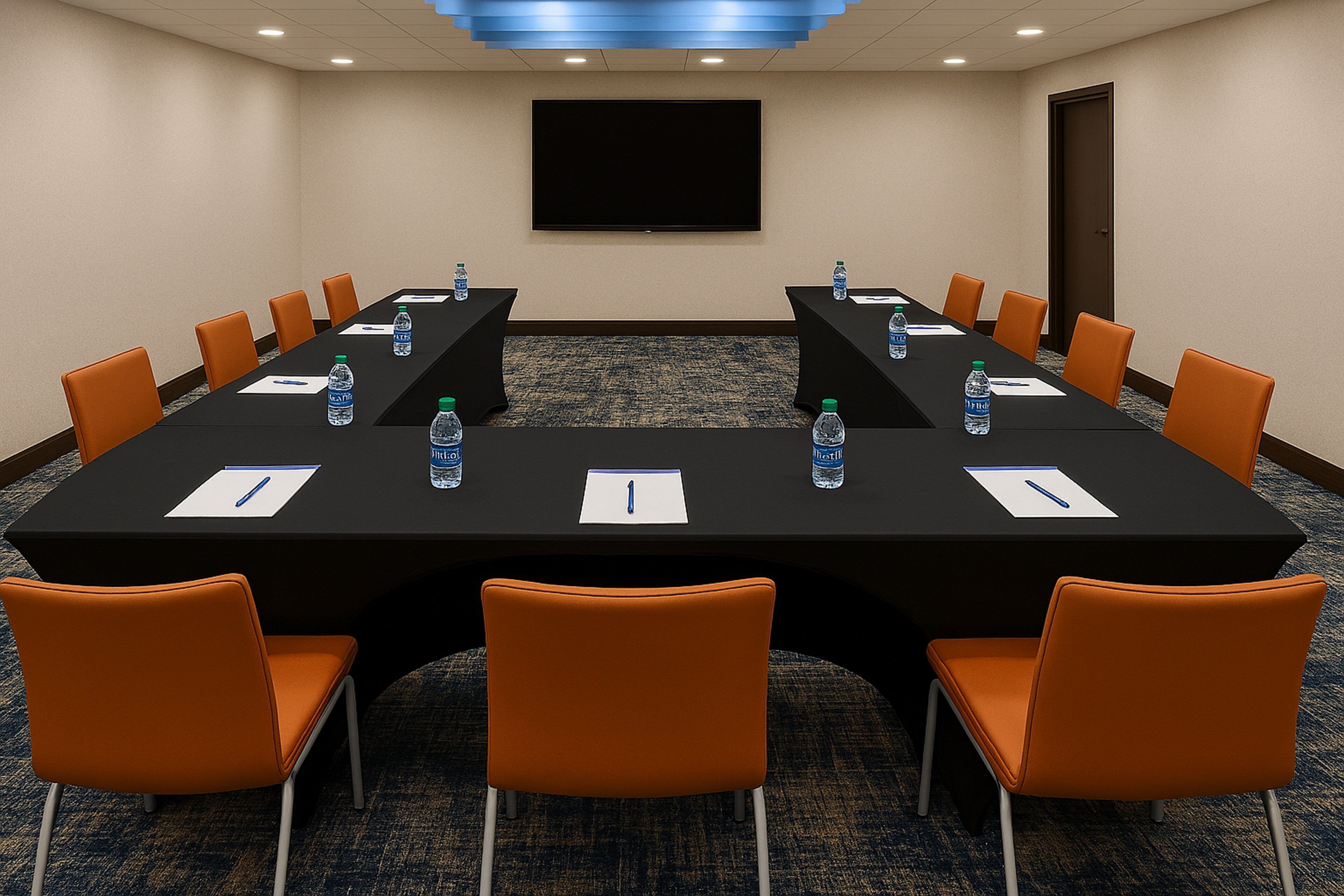 A conference room with a long table, chairs, water bottles, and a TV screen.