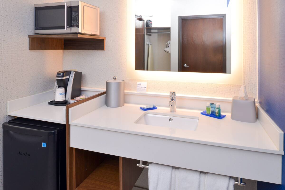 Une salle de bain moderne équipée d’un four à micro-ondes, d’une machine à café, d’un évier et d’un petit réfrigérateur.