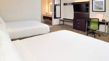 A hotel room with two beds, a desk with a computer, a TV, and a mirror.