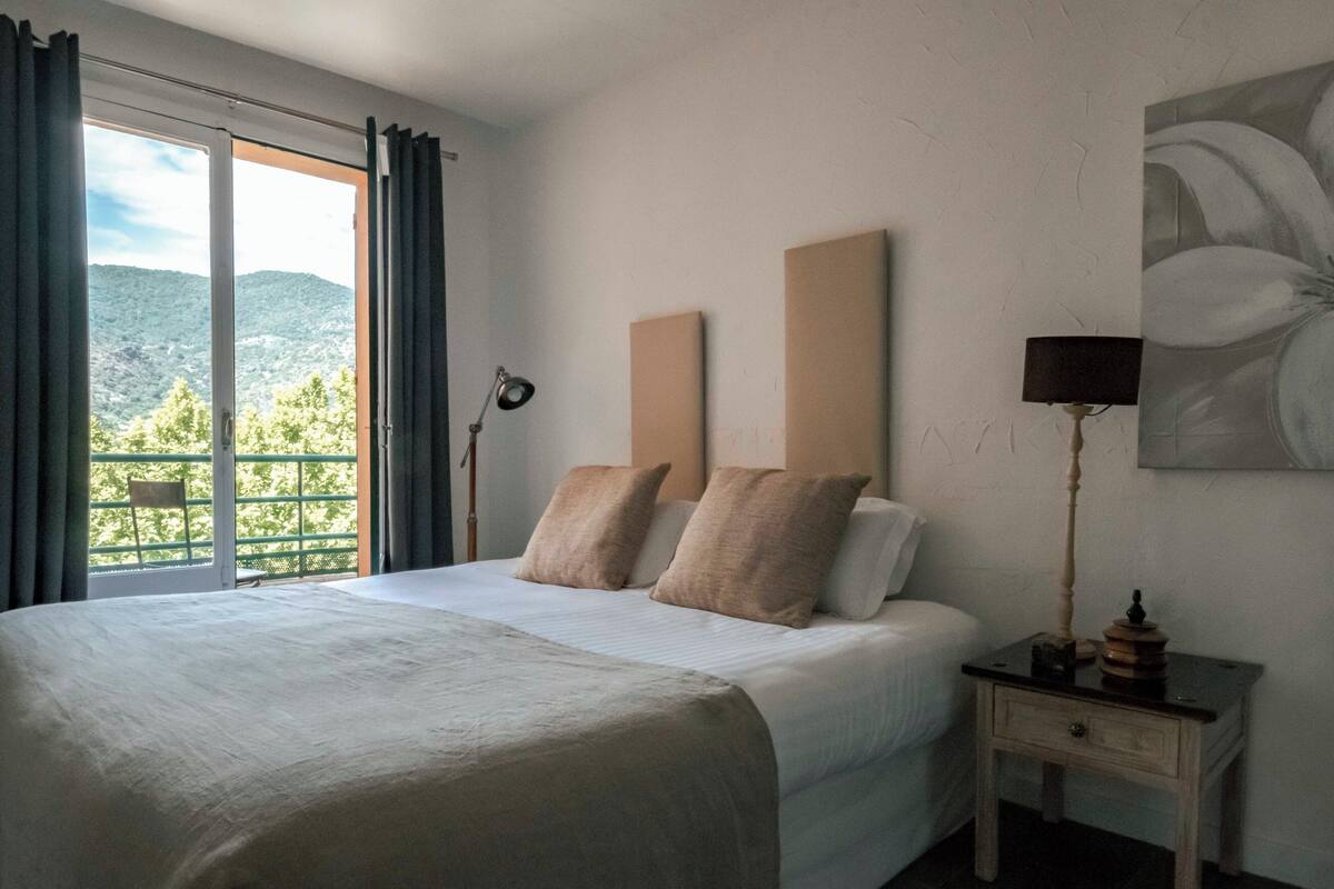 A hotel room with a large bed, a nightstand, a lamp, and a painting on the wall.