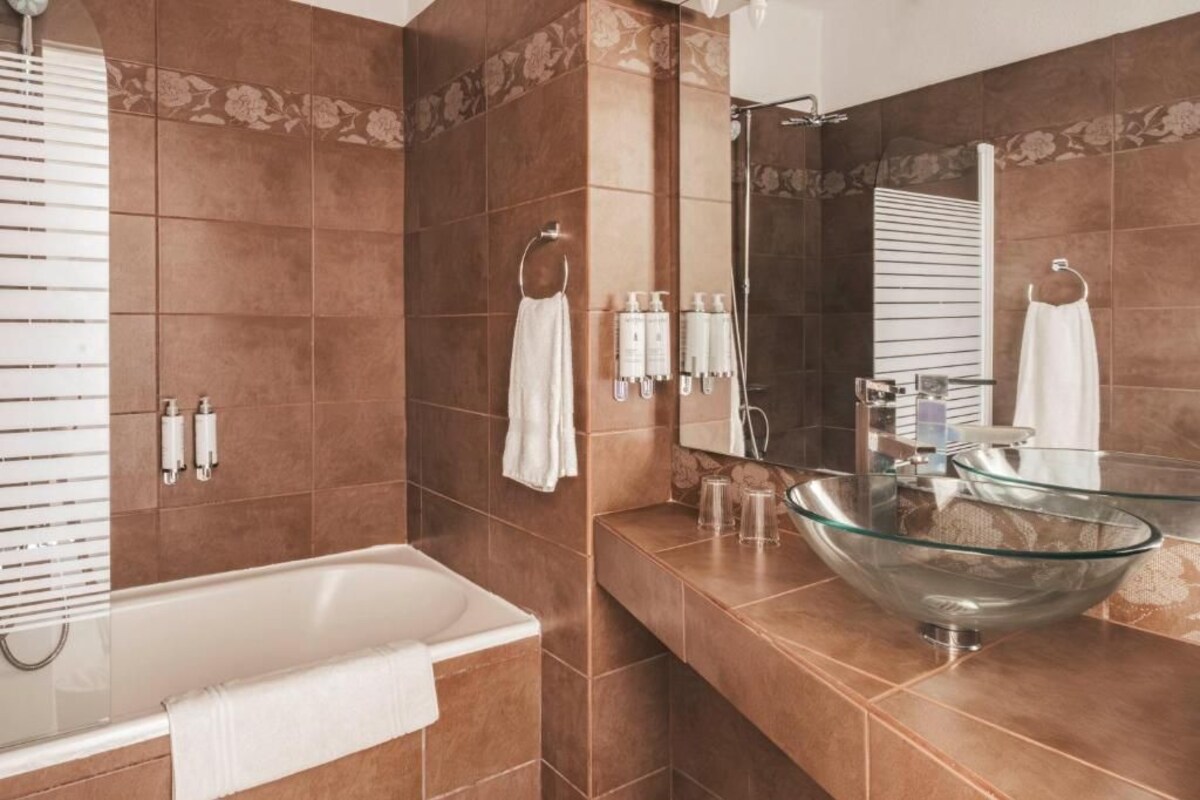 Une salle de bain moderne avec un lavabo en forme de bol en verre, une baignoire et un grand miroir.