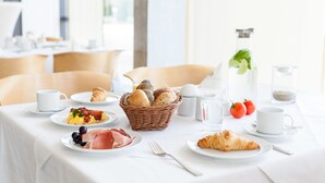 A breakfast table with croissants, eggs, and a bottle of water.