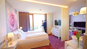 Una habitación de hotel con una cama grande, televisión, escritorio y baño.