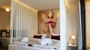A hotel room with a large bed, a bathtub, and a wall with a large image of lips.