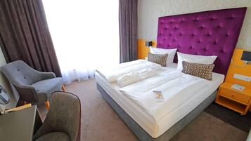 Une chambre d’hôtel avec un grand lit, une chaise, un bureau et une table de chevet.