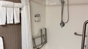 A modern bathroom with a walk-in shower, a towel rack with folded towels, and a set of toiletries.