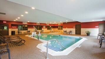 Una piscina interior con una silla de salvavidas, un banco y una planta en maceta.