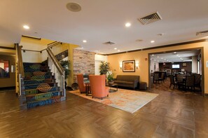 A hotel lobby with a staircase, seating area, and a dining section. - Holiday Inn Express & Suites Chicago-Deerfield/Lincolnshire by IHG (Deerfield)