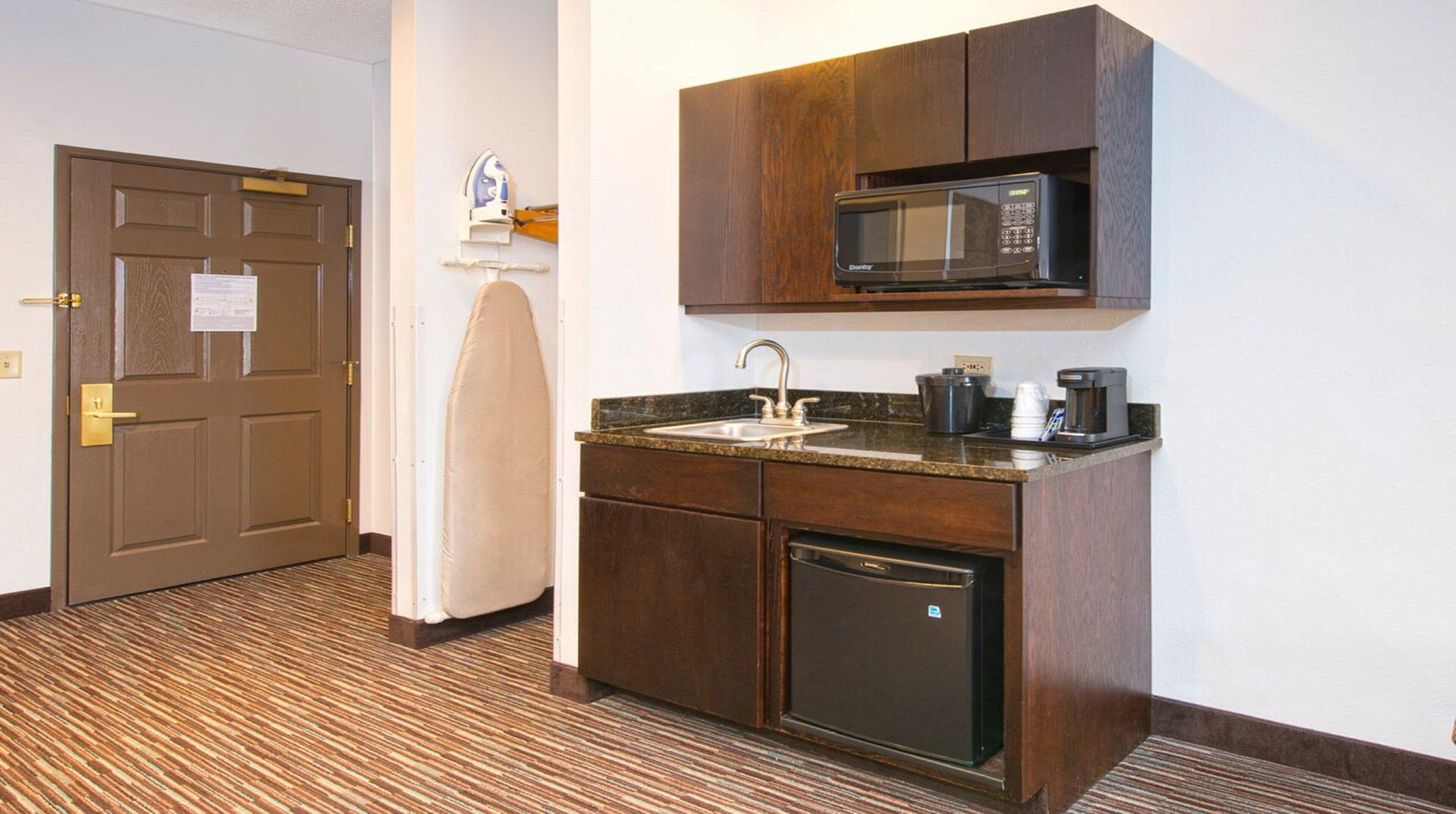 A compact kitchen with a built-in microwave, a coffee maker, and a dishwasher.