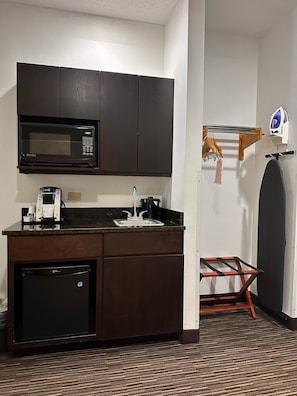 Una cocina compacta equipada con microondas, cafetera y un refrigerador pequeño.