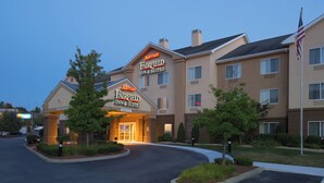 Ett Marriott Fairfield Inn & Suites-hotell med en väl upplyst entré, flera våningar och en flagga.