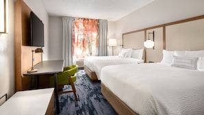A hotel room with two beds, a desk with a chair, a television, and a window with curtains.