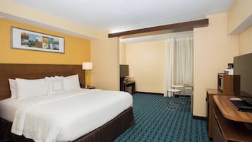Een hotelkamer met een groot bed, een bureau, een televisie en een foto aan de muur.