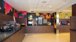 A modern kitchen with wooden cabinets, a stainless steel refrigerator, and a fruit display. - Fairfield by Marriott Inn & Suites Raynham Middleborough/Plymouth (Middleborough)