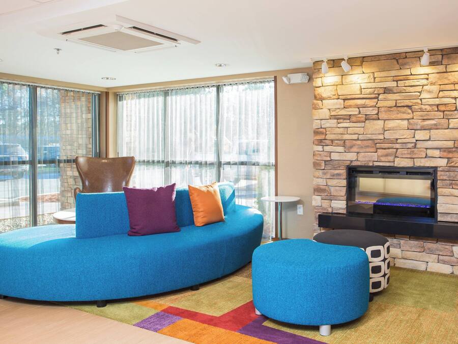 A modern living room with a blue sofa, ottoman, and a stone fireplace.