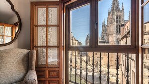 Una habitación con un ventanal que da a un edificio histórico y un balcón de hierro forjado.