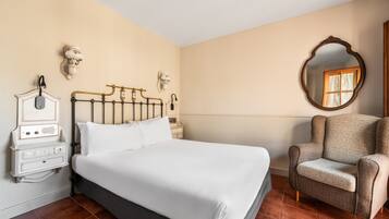 A neatly arranged bedroom with a bed, bedside table, lamp, and a chair.