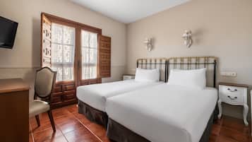 Un dormitorio con dos camas, un escritorio, una silla y un televisor.