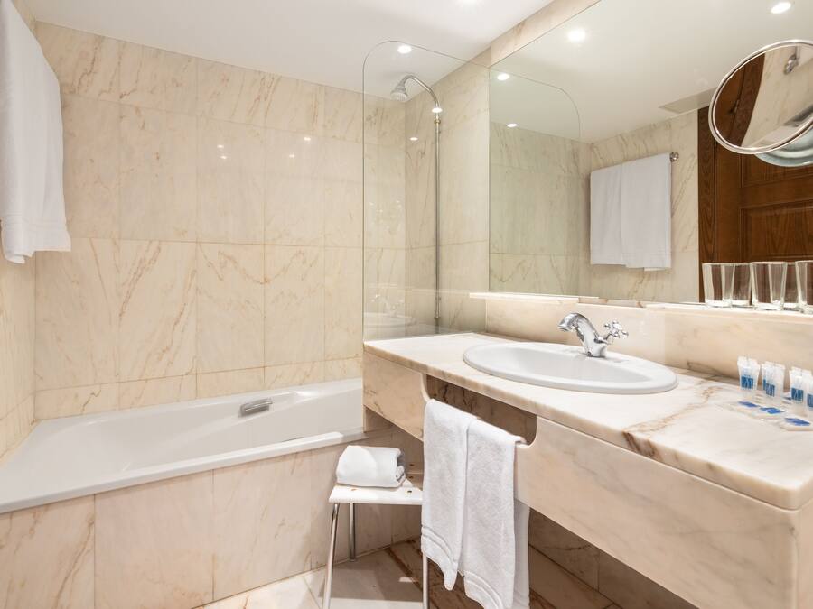 A modern bathroom with a bathtub, a sink, and a large mirror.