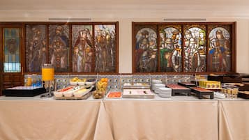 Una mesa de buffet con diferentes alimentos y una ventana de vitral detrás.
