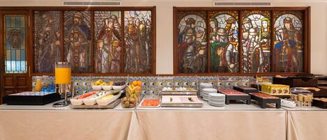 Una mesa de buffet con diferentes alimentos y una ventana de vitral detrás.
