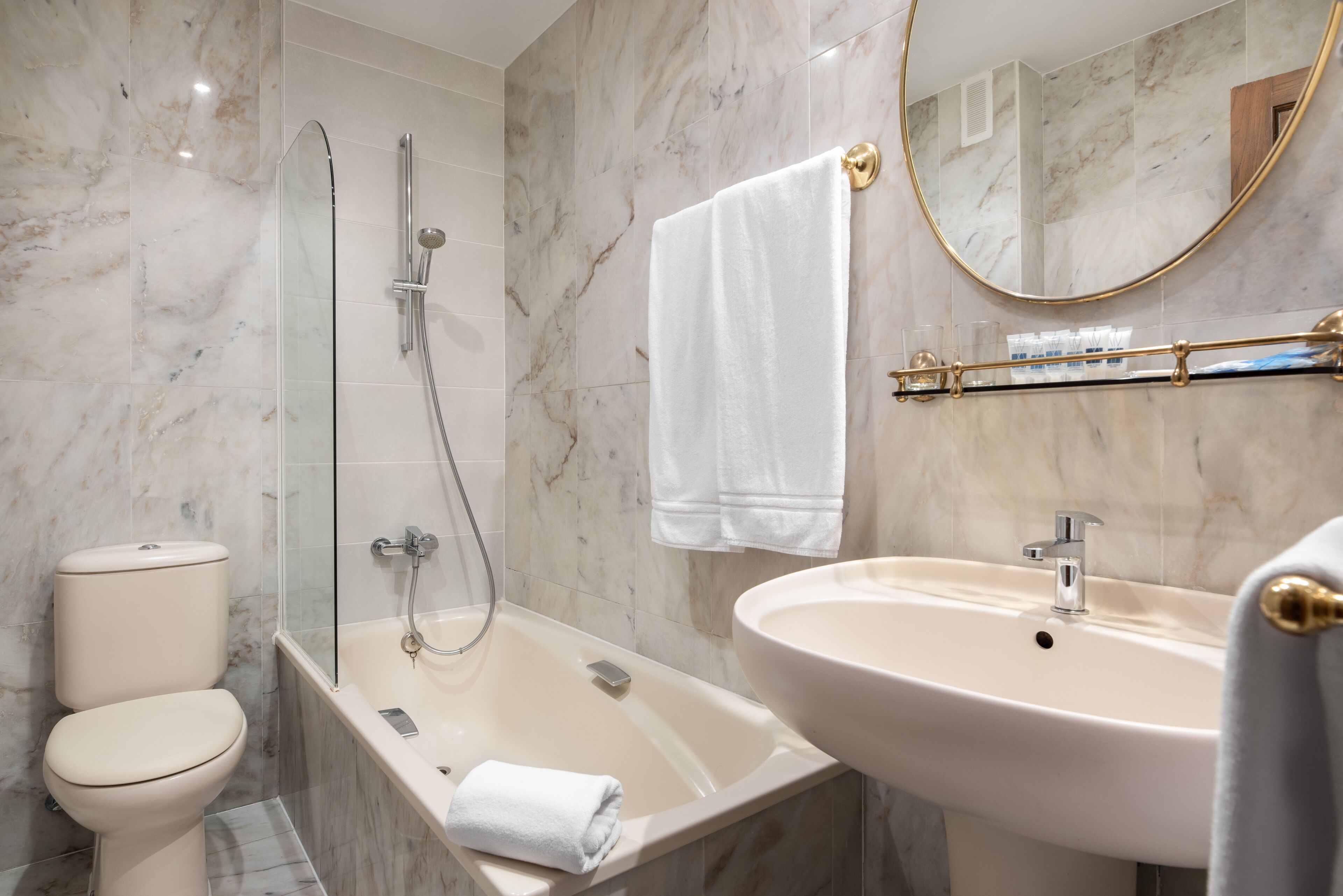 A bathroom with a toilet, a glass-enclosed shower, a bathtub, and a sink.