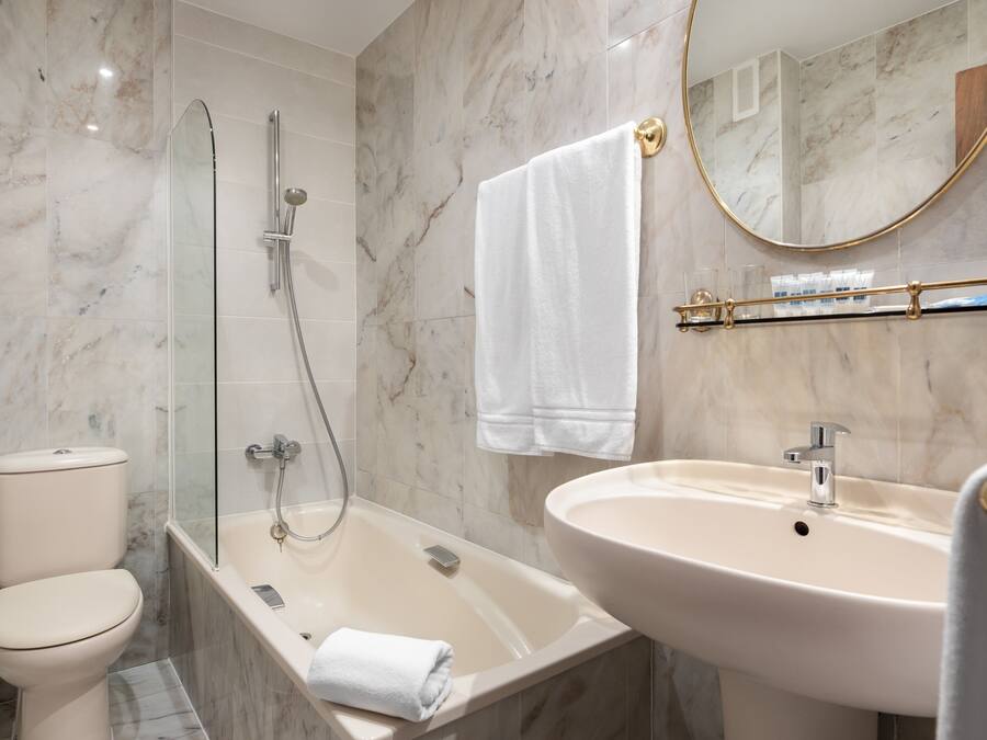 Une salle de bain comprenant des toilettes, une douche à parois de verre, une baignoire et un lavabo.