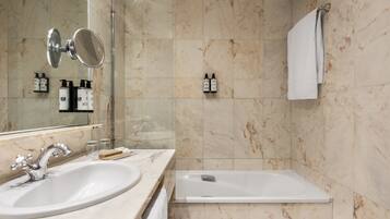 Un baño moderno con lavamanos de mármol, un espejo, ducha y bañera.