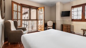 Un dormitorio con una cama grande, una silla, un escritorio y un televisor.