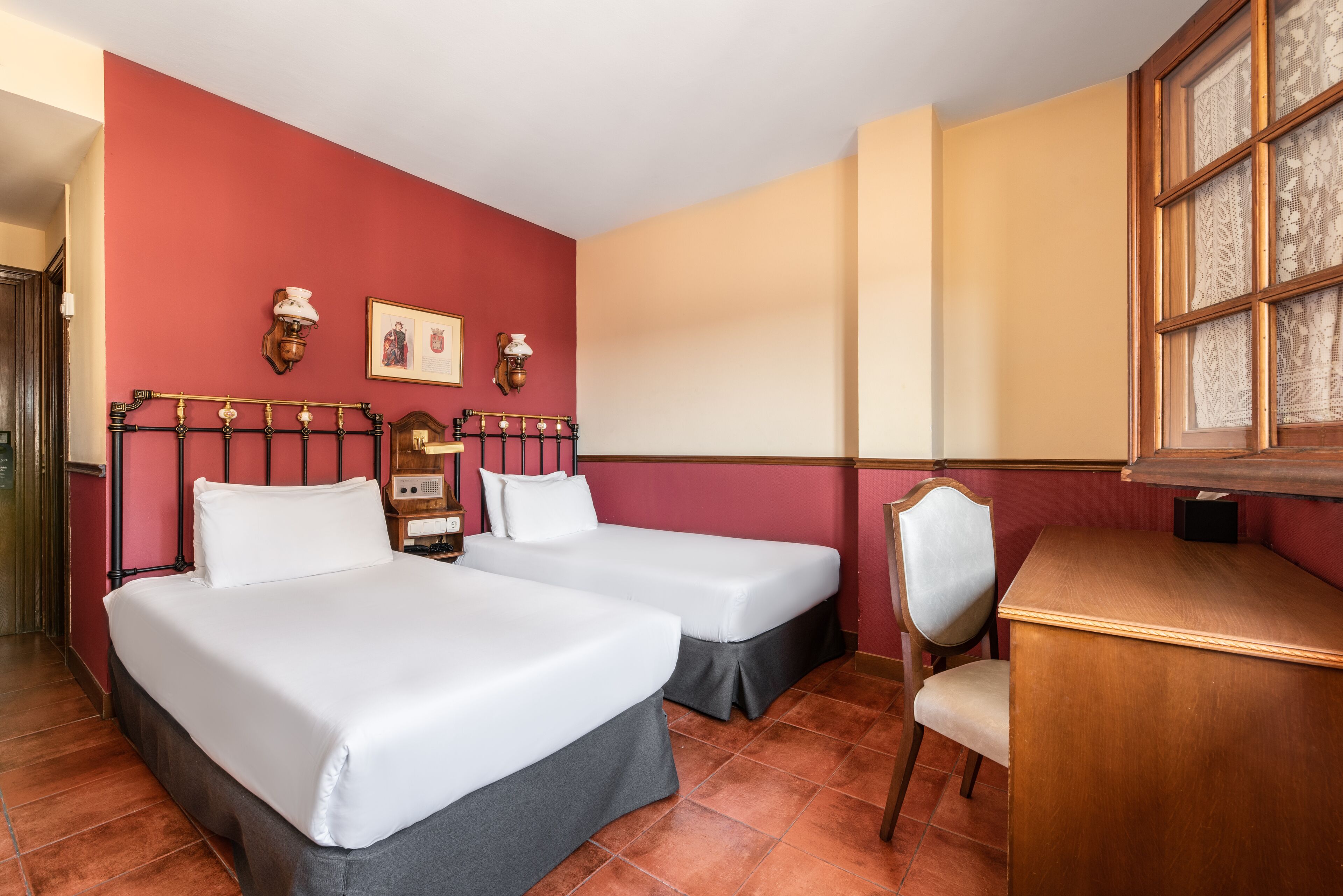 A hotel room with two beds, a desk, and a chair.