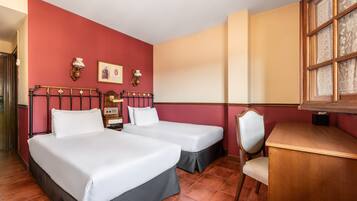 A hotel room with two beds, a desk, and a chair.