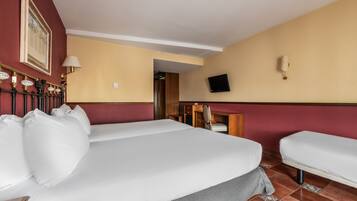 Ein Hotelzimmer mit einem großen Bett, einem Schreibtisch, einem Sessel und einem Fernseher an der Wand.