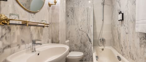Un baño con lavamanos, inodoro y bañera de mármol.