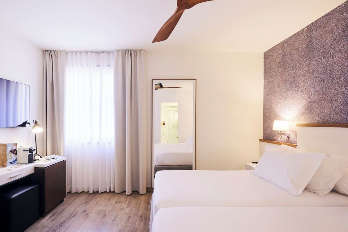 Una habitación de hotel con cama, escritorio, silla, televisor y puerta que da a un baño.