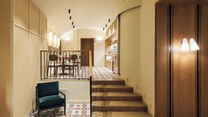 A hotel lobby with a staircase, a dining area, and a seating area with a chair. - H10 Racó del Pi Boutique Hotel (Barcelona)