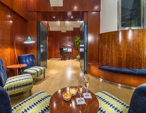 Relax in style with a warm and inviting lounge area featuring a round table, comfortable seating, and a desk for work or reception.