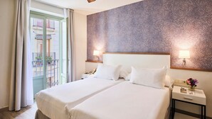 A hotel room with two beds, a balcony, patterned wallpaper, and a ceiling fan. - H10 Racó del Pi Boutique Hotel (Barcelona)