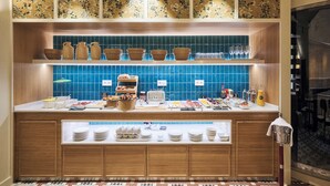 A hotel kitchen with a buffet setup, including various food items, utensils, and a coffee machine. - H10 Racó del Pi Boutique Hotel (Barcelona)