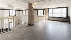 A spacious hotel room with a high ceiling, large windows, and a wooden floor. - Baymont by Wyndham Houston Brookhollow (Houston)
