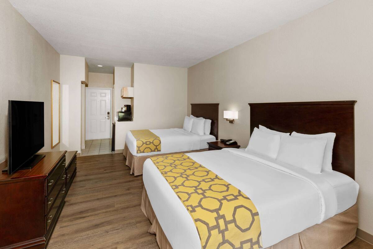 Una habitación de hotel con dos camas, televisión, cómoda y lámpara.