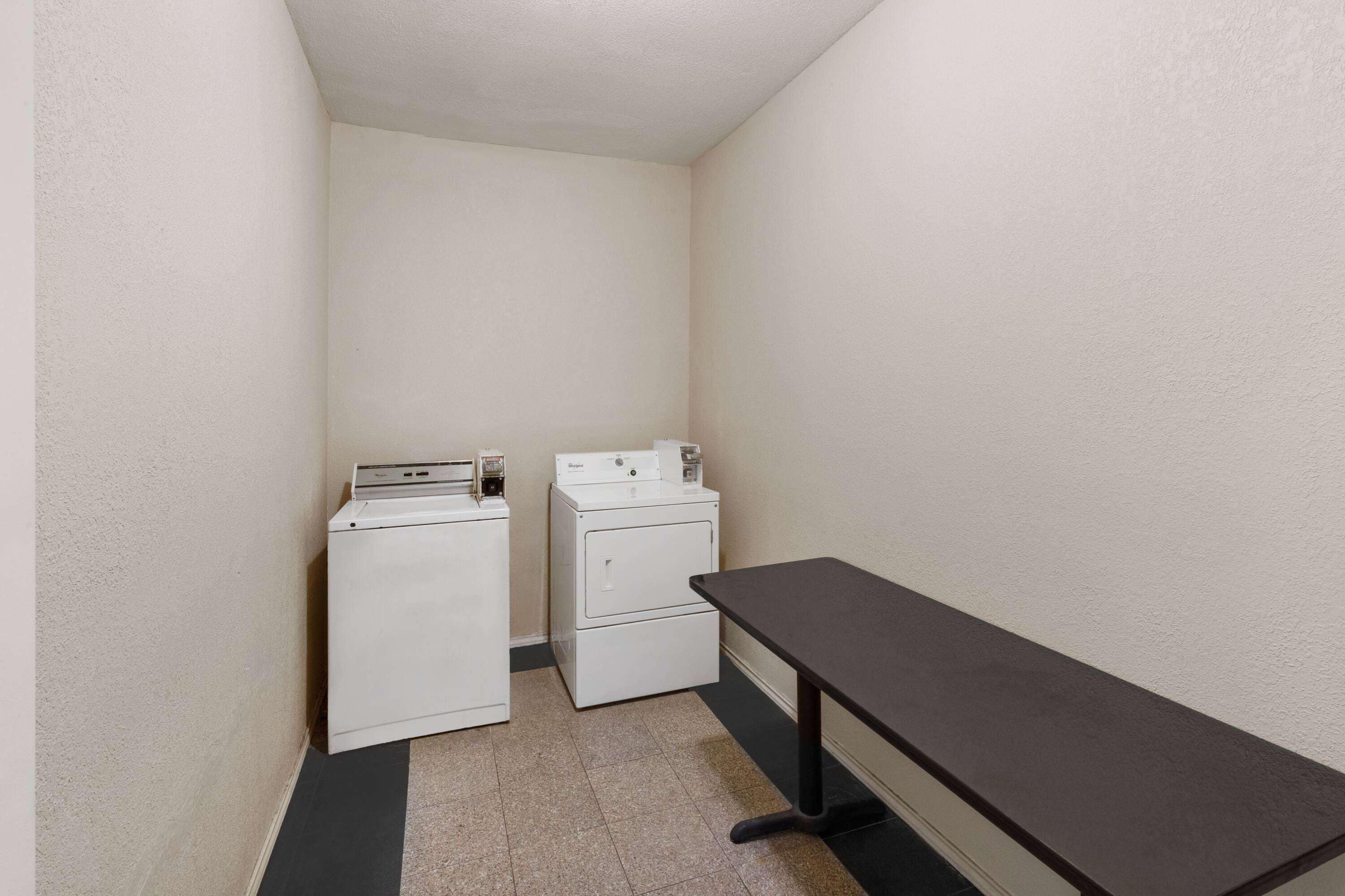 A laundry room with a washing machine, dryer, and a small table.