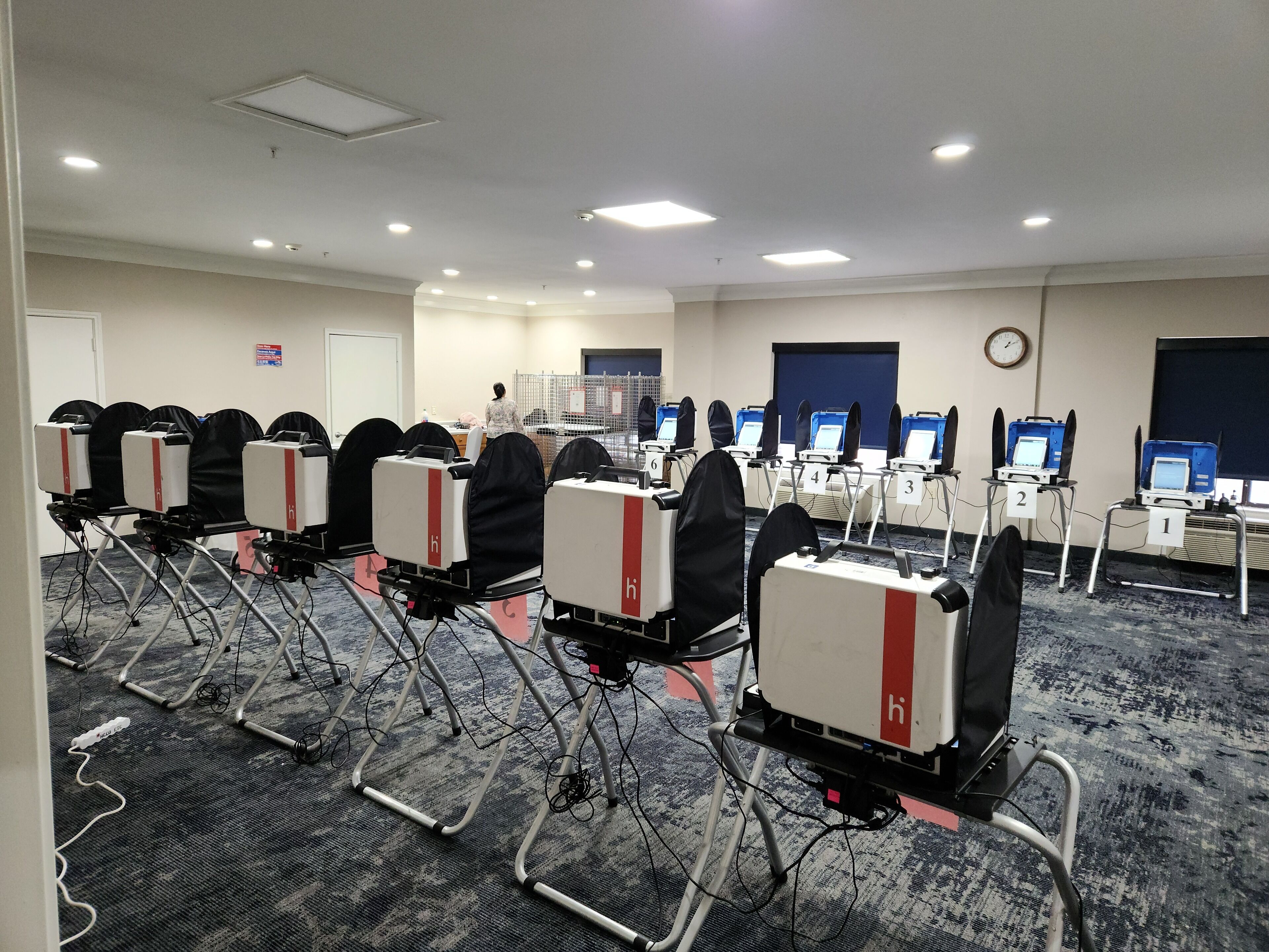 A conference room with rows of tables, each equipped with a laptop and a headset.
